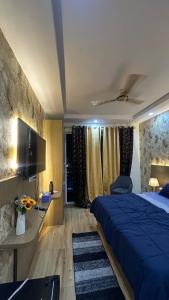 une chambre avec un lit bleu et une télévision à écran plat dans l'établissement Luxurious kaveri, à Greater Noida