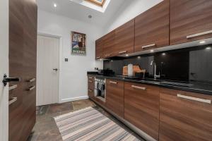 a kitchen with wooden cabinets and a black counter top at Stunning Bowdon Cottage by City SuperHost in Bowdon +27 photos