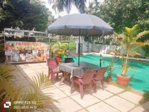 科尔瓦Ave Maria Guest House & Restaurant and Bar的游泳池旁配有桌椅和遮阳伞