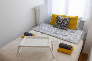 a small bed with a white table and yellow pillows at TOP Location Studio at Deák Sqr in Budapest