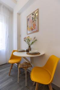 a dining room with a table and two yellow chairs at TOP Location Studio at Deák Sqr in Budapest