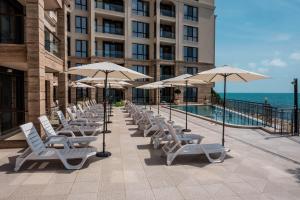 a row of lounge chairs and umbrellas next to a building at Cabacum Pleasure Beachfront Apartments in Varna City