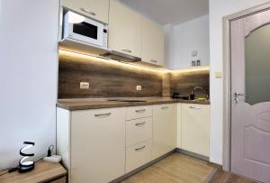 a kitchen with white cabinets and a microwave at Cabacum Pleasure Beachfront Apartments in Varna City