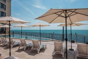 a patio with chairs and umbrellas and the ocean at Cabacum Pleasure Beachfront Apartments in Varna City +9 photos