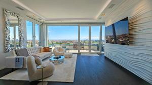 Una sala de estar con un sofá y grandes ventanales. en Munichs No1 Luxury Sky Terrace Penthouse with Unlimited Panoramic City and Alps Views, en Múnich