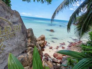 a beach with some rocks and the ocean at Sleepymoon Hostel in Thongsala
