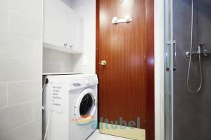 a bathroom with a washing machine and a wooden door at Edificio Esmeralda in Peniscola