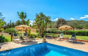 a villa with a swimming pool with chairs and umbrellas at Can Andreuet in Sant Carles de Peralta