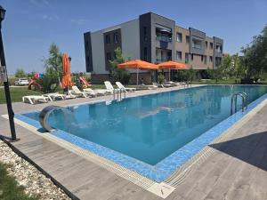 a large swimming pool with chairs and umbrellas next to a building at Isa Residence - Otopeni Airport & Therme I Libertatii Gardens - free pool facilities in Otopeni