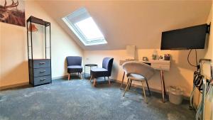 a room with two chairs and a desk and a television at Birchbank House in Roybridge