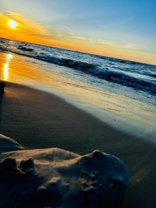 a sunset on a beach with the ocean at Domki Alkana - domek 4 in Nowęcin +3 photos