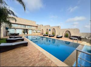 a swimming pool with lounge chairs in front of a building at Tanger Achakar in Tangier