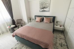 a bedroom with a large bed with pink pillows at Isa Residence - Otopeni Airport & Therme I Libertatii Gardens - free pool facilities in Otopeni +11 photos