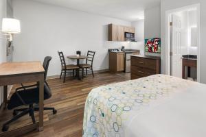 a hotel room with a bed and a desk and a kitchen at HomeTowne Studios & Suites by Red Roof Charlotte - Ballantyne in Charlotte