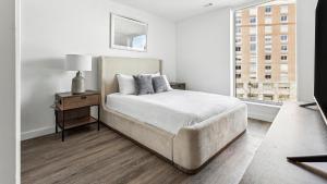 a white bedroom with a bed and a window at Landing at eXchange - Downtown Detroit in Detroit
