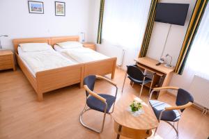 a bedroom with a bed and a table and chairs at Hotel Gästehaus Lutgen in Waldfeucht