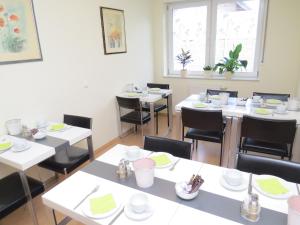 a dining room with white tables and black chairs at Hotel Gästehaus Lutgen in Waldfeucht