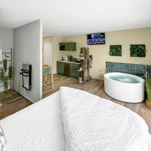 una camera da letto con vasca e cucina di La Parenthèse Végétale - Maison cosy et apaisante a Rang-du-Fliers