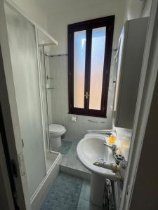 a bathroom with a sink and a toilet and a window at Marisa Apartment in Reggio di Calabria