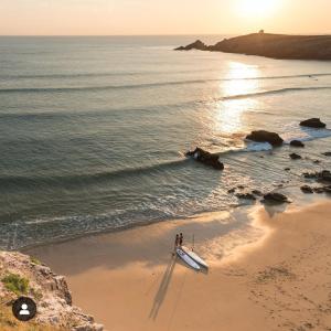 キブロンにあるAppartement proche de la grande plageのボートのある浜辺に立っている二人