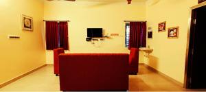 a living room with a red couch and a television at Royal Black Pepper Cottage in Yercaud