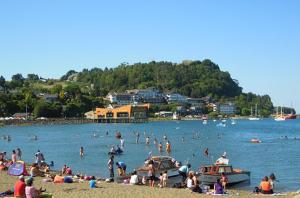 a group of people on a beach with boats in the water at Habitación a pasos de la playa in Puerto Varas