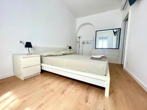 a white bedroom with a large bed and a window at La casa di Mariposa in Sanremo
