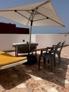 a table and chairs and an umbrella on a patio at Appartement à louer aourir Tamraght in Aourir
