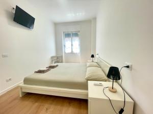 a white bedroom with a bed and a table with a lamp at La casa di Mariposa in Sanremo