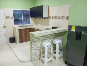 a kitchen with a counter and two stools in it at Apartamentos el farol in Ciénaga