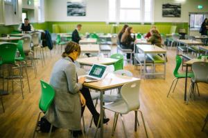 a woman sitting at a table with a laptop in a classroom at Carrock Hall, University of Cumbria Carlisle in Carlisle