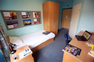 a small room with a bed and a desk with a laptop at Carrock Hall, University of Cumbria Carlisle in Carlisle