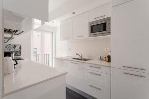 a white kitchen with a sink and a microwave at GuestReady - Modern flat near Estrela Garden in Lisbon +20 photos