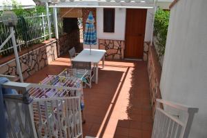 een terras met een tafel, stoelen en een parasol bij Villa Eugenia - Mondello Beach in Palermo +10 foto's