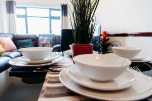 una mesa de madera con tazones y platos blancos. en Shoebury Lodge near Sea front In Southend, en Southend-on-Sea