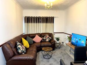 sala de estar con sofá de cuero marrón y TV en Shoebury Lodge near Sea front In Southend, en Southend-on-Sea