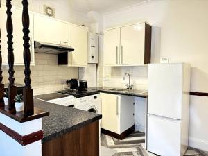 Una cocina con gabinetes blancos y un refrigerador blanco. en Shoebury Lodge near Sea front In Southend, en Southend-on-Sea 30 fotos más