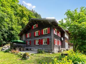 a wooden house with red shutters in a forest at Waldhüsle in Ausserwald