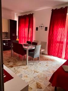 a dining room with red curtains and a table and chairs at The contineltal in Pachino +5 photos