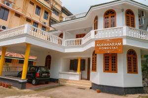 a white building with a sign in front of it at Guruvayur Agraharam Homestay in Guruvāyūr