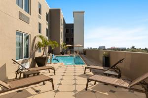 a patio with benches and a swimming pool on a building at Holiday Inn Express Fort Lauderdale Airport South by IHG in Dania Beach