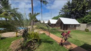 a house with a palm tree in front of a yard at Fantastiscos bangalôs em Aracaju in Aracaju