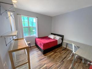 ein kleines Schlafzimmer mit einem roten Bett und einem Fenster in der Unterkunft Corporate Suite Midtown Wilmington in Wilmington + 21 Fotos