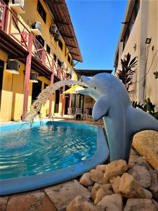une statue de dauphins à côté d'une piscine dans l'établissement Pousada Coco Verde Natal, à Natal