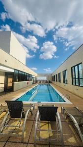einem Pool mit zwei Stühlen vor einem Gebäude in der Unterkunft Quarto Mobiliado no Hotel Comfort Taguatinga com Wi-Fi, Ar condicionado e Estacionamento Grátis in Brasilia