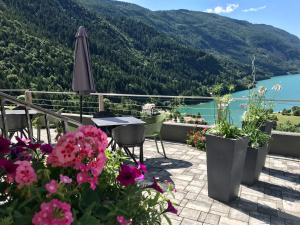 a patio with a table and chairs and flowers at Hotel Aurora in Molveno
