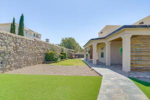 a house with a stone wall and green grass at Family-Friendly El Paso Home Hike, Shop and Explore in Santa Teresa