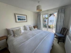 a bedroom with a large white bed with a window at Suzetta Cottage in Seaview