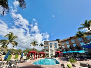 a pool at a hotel with palm trees and a building at Holiday Inn Express & Suites Naples Downtown - 5th Avenue by IHG in Naples