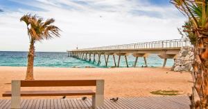 a bench sitting on a beach with a pier at BArcelona BAdalona Relax PLAYA y METRO in Badalona